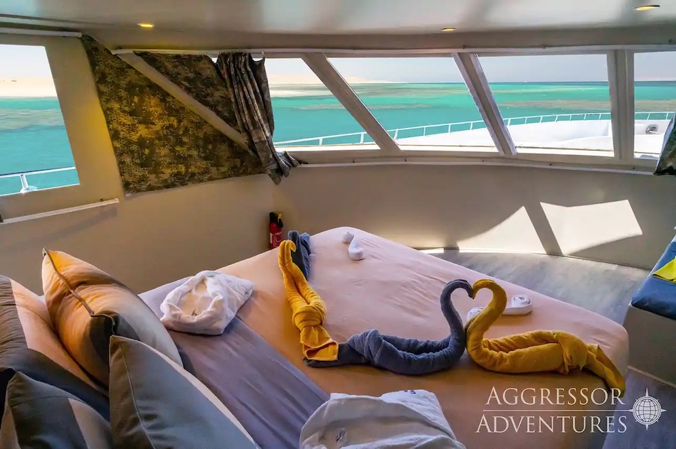 Elegant cabin on a yacht with a view of the turquoise sea, towels in the shape of animals.