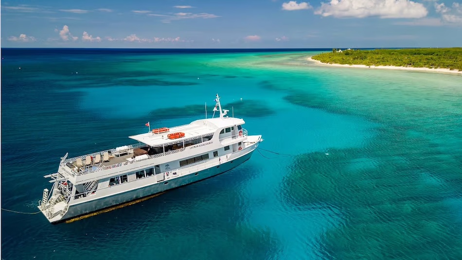 Dive boat moored on turquoise sea, reefs visible underwater.