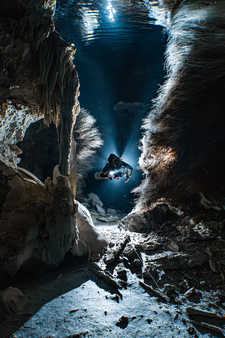 Diving in an illuminated underwater cave, revealing spectacular formations and an adventurous explorer.