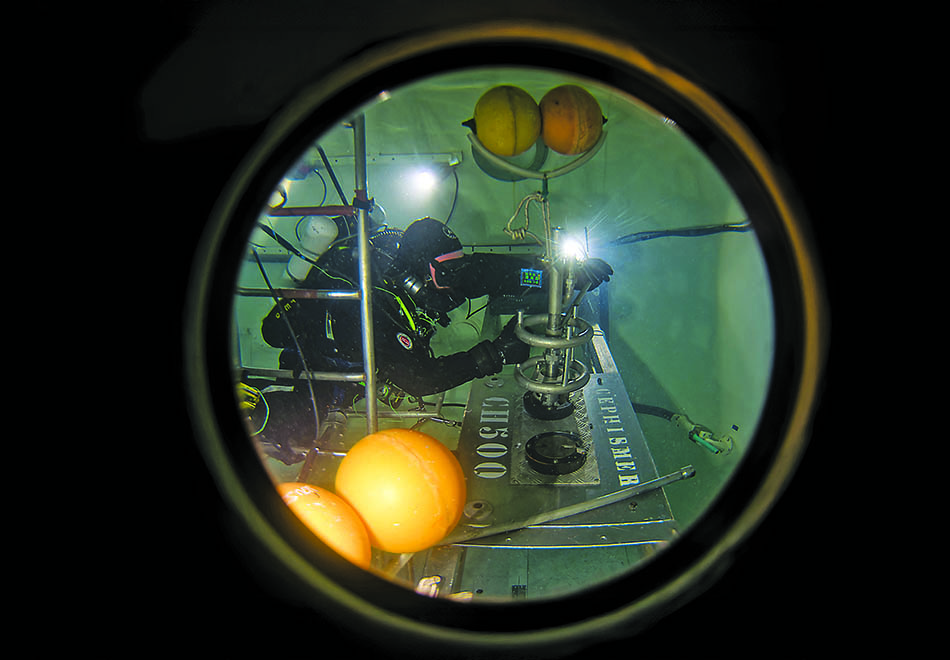 A diver conducts underwater research with specialized equipment in an aquatic environment.