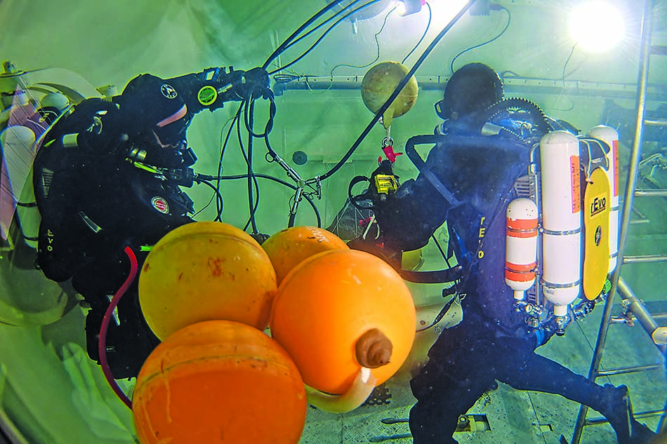 Divers equipped working underwater, using buoys for underwater missions.