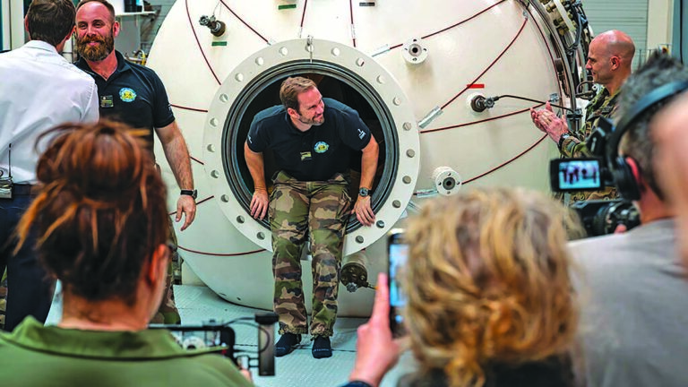 Des plongeurs émergent d'une chambre de décompression, illustrant les défis de l'exploration sous-marine.