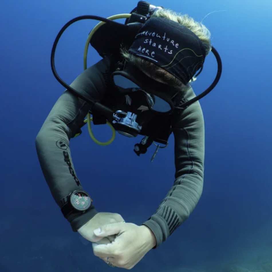 Diver exploring the ocean depths with appropriate diving gear and a waterproof watch.
