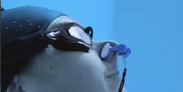 Plongeur en apnée observant l'environnement sous-marin, équipé de lunettes adaptées.