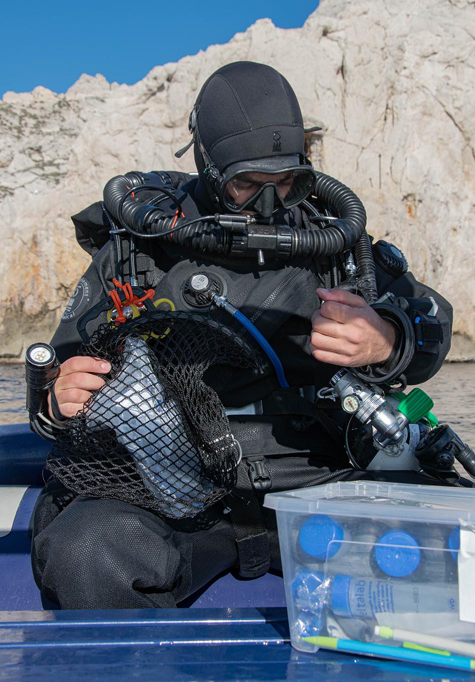 Diver preparing their equipment for an underwater exploration in a coastal environment.