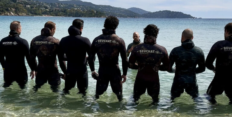 Un groupe de plongeurs en combinaison Beuchat se prépare pour une aventure sous-marine dans des eaux cristallines.