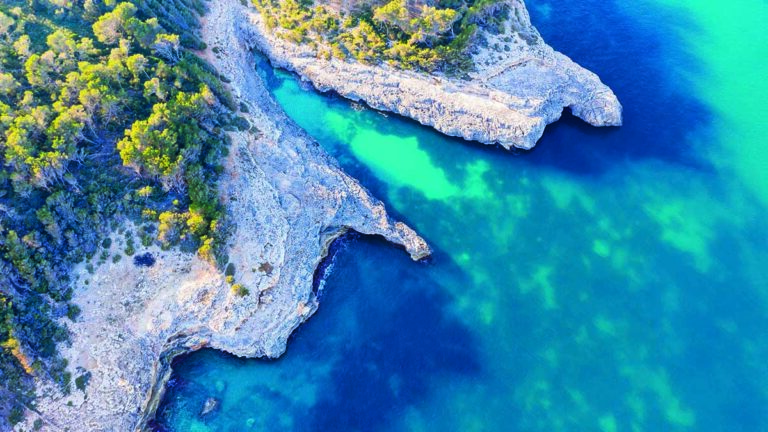 Côte rocheuse aux eaux turquoise, idéale pour la plongée et l'exploration sous-marine. Photo © Martin Siepmann / Alamy
