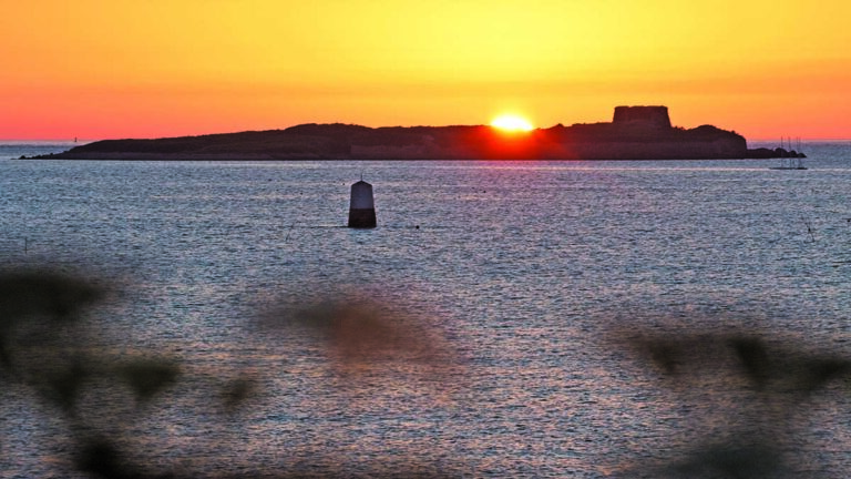 Coucher de soleil sur une île, révélant un paysage marin idéal pour la plongée sous-marine.