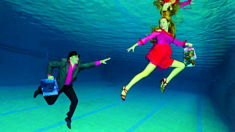 Un couple en tenue colorée évolue dans un environnement sous-marin, illustrant la magie de la plongée.